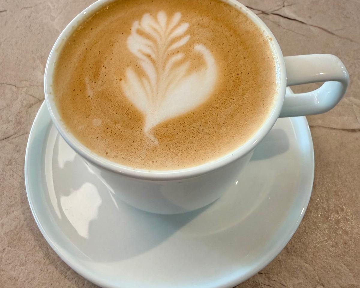 Cappuccino mit Latte-Art in heller Tasse auf einem Marmortisch