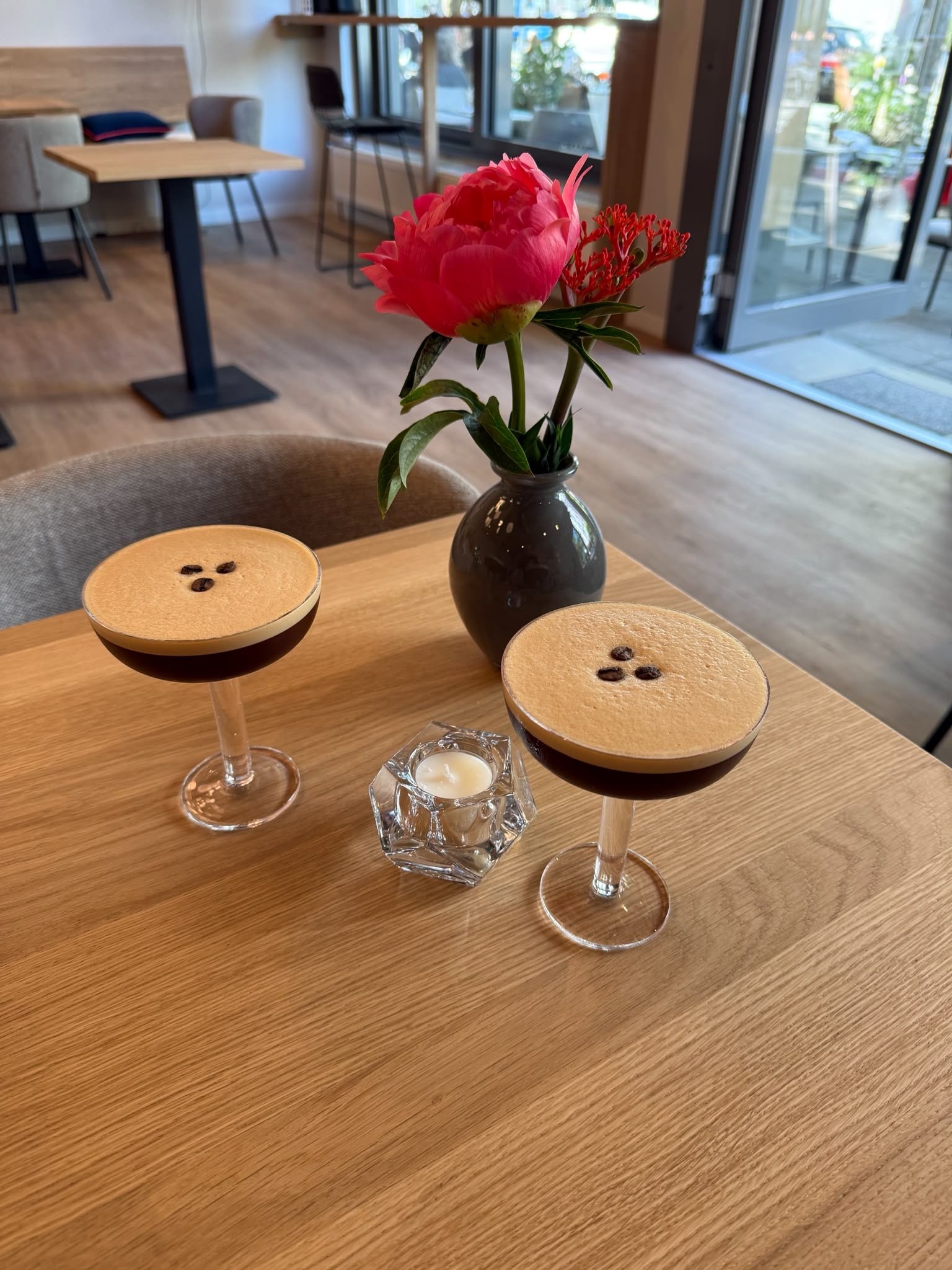 Zwei Espresso Martini auf einem Holztisch mit Blumenvase